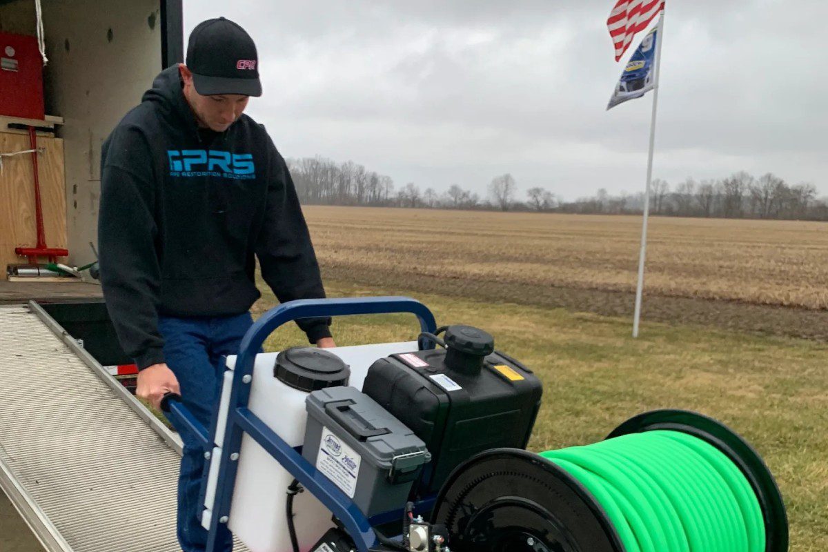 A man standing next to a cart with two sprayers.